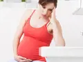 Gravid kvinna med handen mot pannan, känner sig illamående sent i graviditeten.