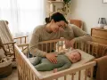 Mamma tittar kärleksfullt på sin snorig bebis som sover i spjälsängen.