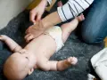 En person byter blöja på en bebis. Frågan "hur ofta bajsar bebis" är relevant för många föräldrar.