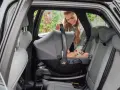 En leende mamma placerar en baby i en Britax Baby Safe Core bilbarnstol i en bil.