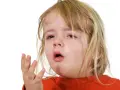 Ett litet barn med rött linne och blont hår, med tårfyllda ögon och öppen mun, som om det hostar på natten.