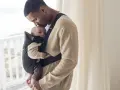 Pappa kysser sin bebis som bärs i en svart Babybjörn Mini Mesh bärsele.