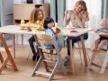 Familjen samlas kring bordet, barnen sitter i sina kinderkraft enock barnstolar och njuter av frukosten.