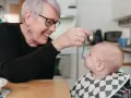 Glad mormor matar bebis med smakportioner. Första maten för en 4 månader gammal bebis.