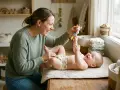 Mother playing with her happy baby on a changing mat, holding a giraffe toy.