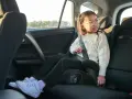 Flicka i bilens baksäte sitter på bälteskuddar och är fastspänd.