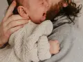 En bebis drar sig i håret medan den vilar i sin pappas famn.