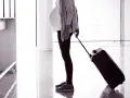 Gravid kvinna med resväska på flygplatsen, redo att flyga gravid.