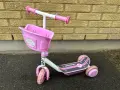 En rosa stiga sparkcykel trehjuling med korg framtill, redo för äventyr.