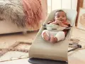 Söt bebis i beige Babybjörn babysitter. Denna babysitter klarar en babybjörn babysitter maxvikt på 13 kg.