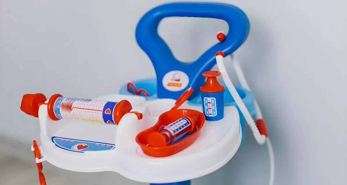 Lekfullt set med doktorsleksaker i blått och orange, inklusive en spruta med hjärtmönster och en medicinflaska.
