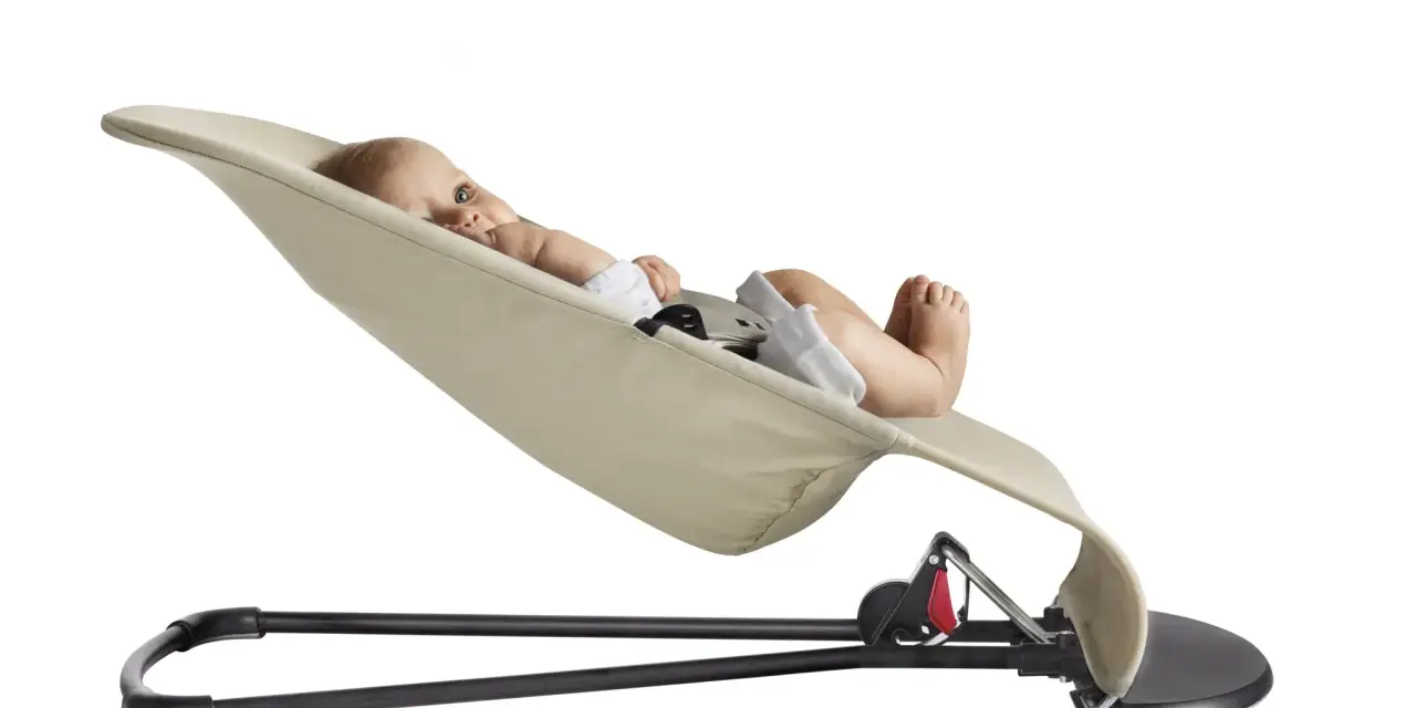 En bebis ligger bekvämt i en beige Babybjörn Balance Soft.