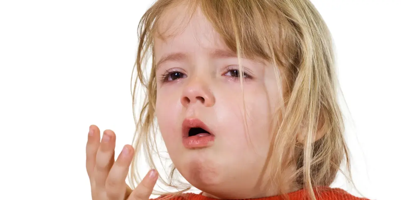 Ett litet barn med rött linne och blont hår, med tårfyllda ögon och öppen mun, som om det hostar på natten.