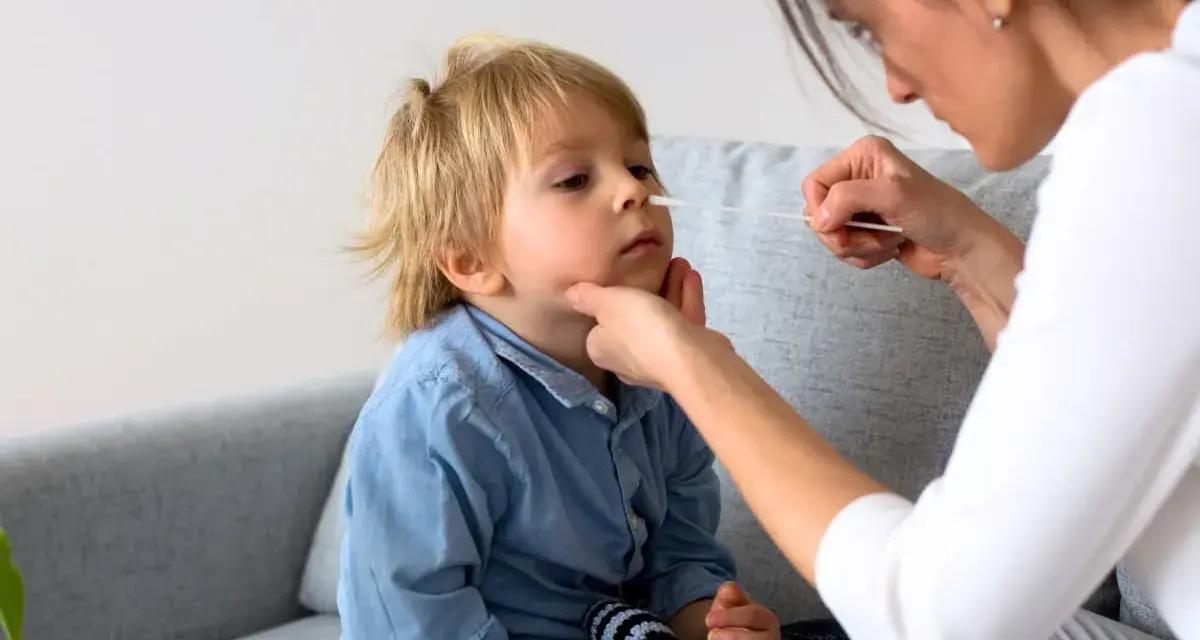 En mamma tar ett covidprov på sitt barn. Liten covid bebis får ett snabbt test.