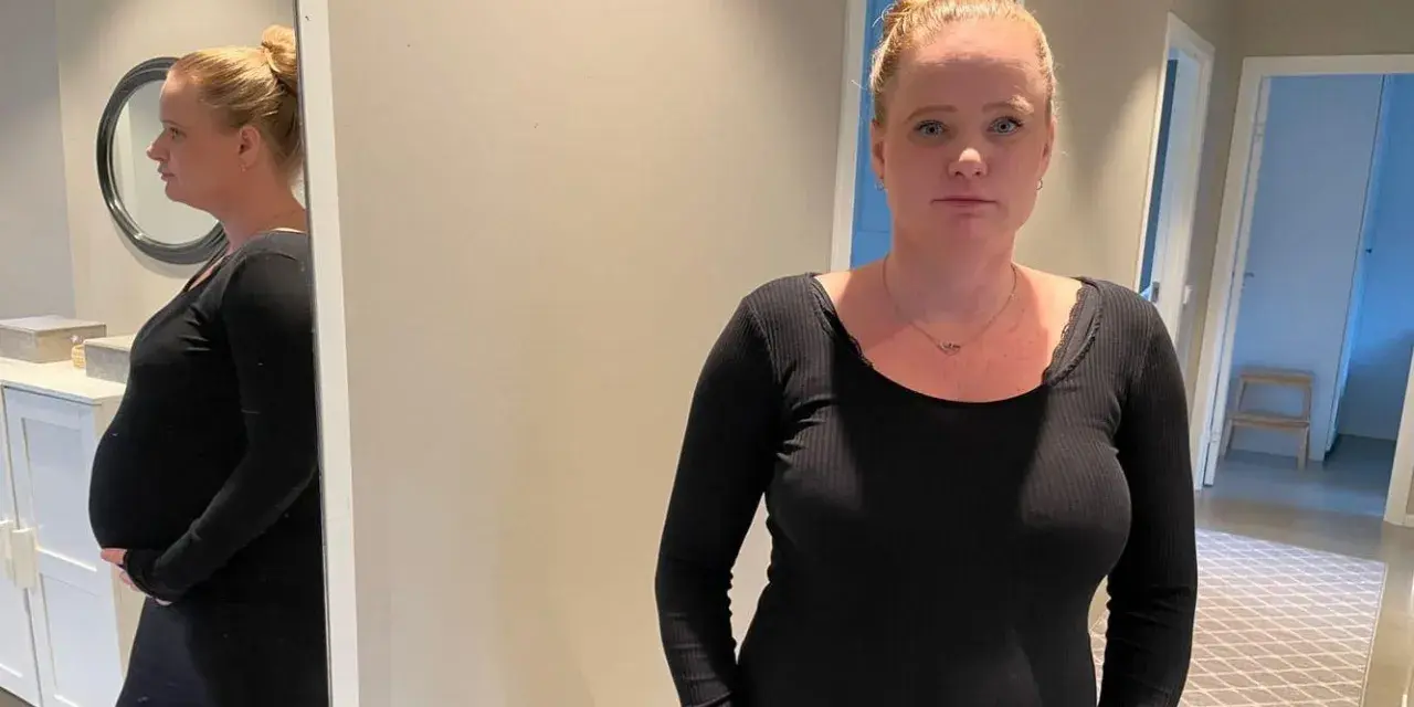 Gravid kvinna med stressad blick, med sin mage synlig. Hon funderar på hur hon ska hantera gravid stress på jobb.
