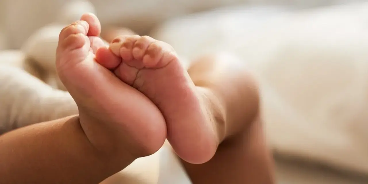 Små babyfötter vilar mot en mjuk kudde. Kanske snart dags för en potta med ljud för att öva på att bli stor.