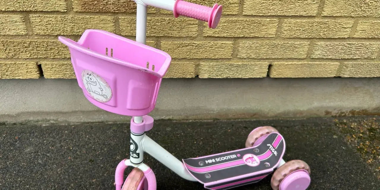 En rosa stiga sparkcykel trehjuling med korg framtill, redo för äventyr.