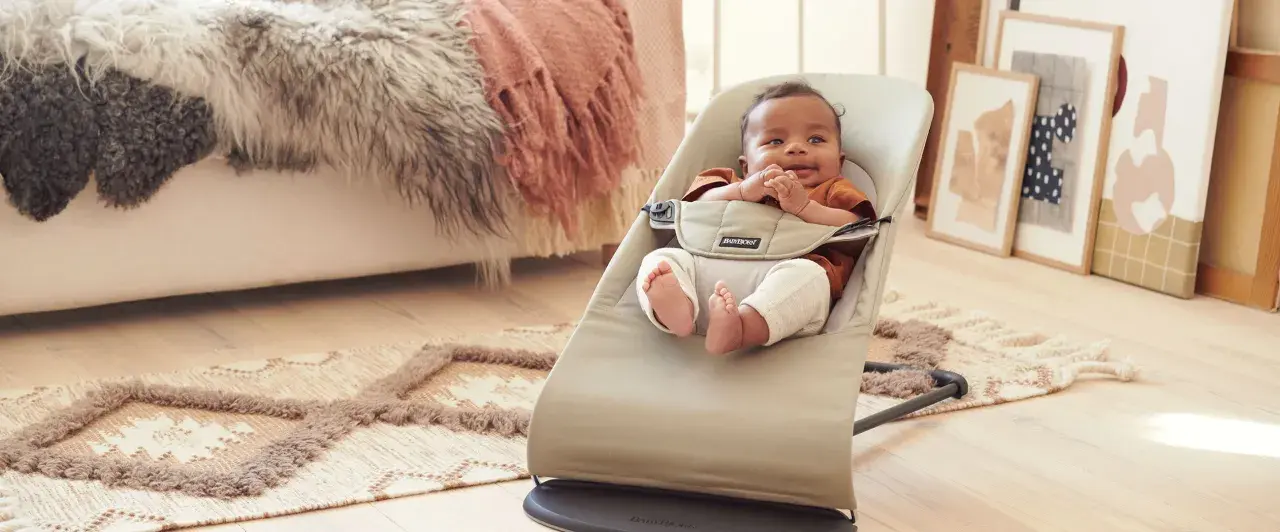 Söt bebis i beige Babybjörn babysitter. Denna babysitter klarar en babybjörn babysitter maxvikt på 13 kg.