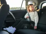 Flicka i bilens baksäte sitter på bälteskuddar och är fastspänd.