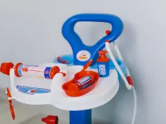 Lekfullt set med doktorsleksaker i blått och orange, inklusive en spruta med hjärtmönster och en medicinflaska.