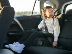 Flicka i bilens baksäte sitter på bälteskuddar och är fastspänd.