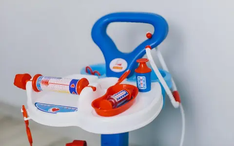 Lekfullt set med doktorsleksaker i blått och orange, inklusive en spruta med hjärtmönster och en medicinflaska.