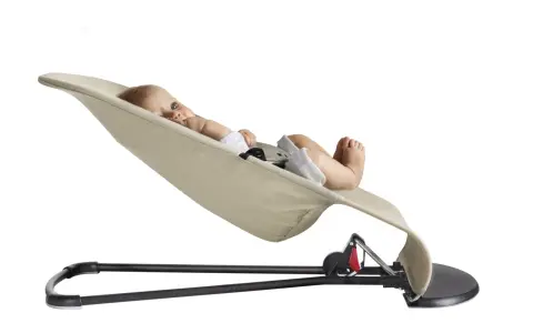 En bebis ligger bekvämt i en beige BabyBjörn babysitter.