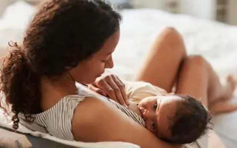 En mamma ammar sin nyfödda bebis. Den lilla bebisen, bara 2 veckor gammal, vill amma hela tiden och söker närhet hos sin mamma.