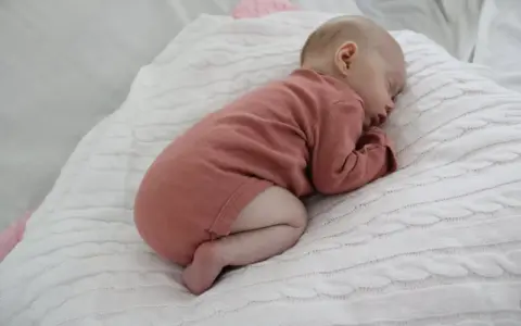 Sover sött i rosa kläder, en bebis under 1 år. Kanske drömmer om hostmedicin barn under 1 år som kan hjälpa vid förkylning.