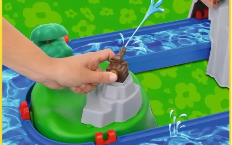 En hand aktiverar en vattenpump på en Aquaplay mountain lake-lekplats, som sprutar vatten genom en blå kanal.