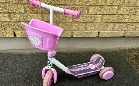 En rosa stiga sparkcykel trehjuling med korg framtill, redo för äventyr.