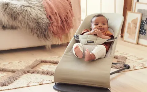 Söt bebis i beige Babybjörn babysitter. Denna babysitter klarar en babybjörn babysitter maxvikt på 13 kg.
