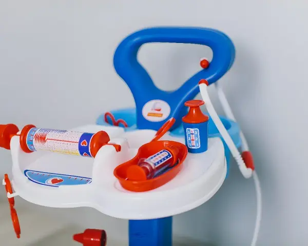 Lekfullt set med doktorsleksaker i blått och orange, inklusive en spruta med hjärtmönster och en medicinflaska.