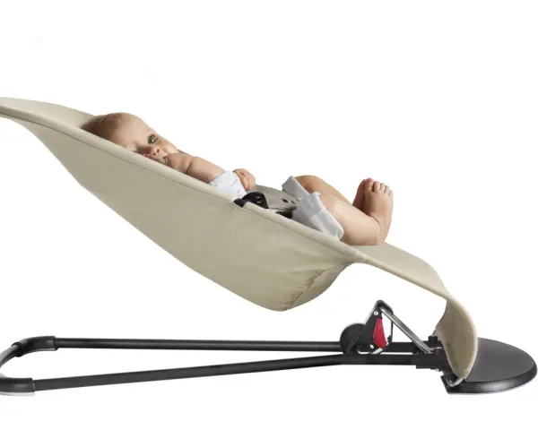 En bebis ligger bekvämt i en beige BabyBjörn babysitter.