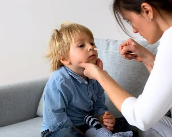 En mamma tar ett covidprov på sitt barn. Liten covid bebis får ett snabbt test.
