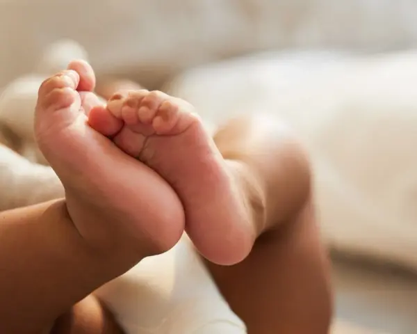 Små babyfötter vilar mot en mjuk kudde. Kanske snart dags för en potta med ljud för att öva på att bli stor.