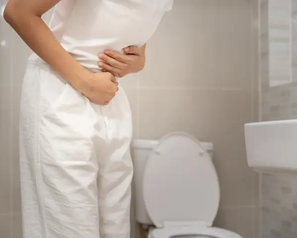 Person med magont i badrummet, möjligen tidig graviditet med diarré.