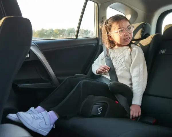 Flicka i bilens baksäte sitter på bälteskuddar och är fastspänd.