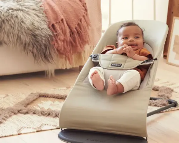 Söt bebis i beige Babybjörn babysitter. Denna babysitter klarar en babybjörn babysitter maxvikt på 13 kg.
