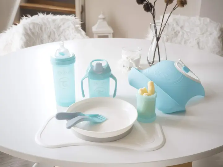 Blå babyutrustning från Twistshake, inklusive flaskor, tallrik, bestick och en praktisk twistshake haklapp.