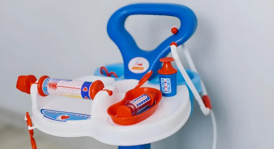 Lekfullt set med doktorsleksaker i blått och orange, inklusive en spruta med hjärtmönster och en medicinflaska.