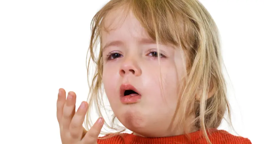 Ett litet barn med rött linne och blont hår, med tårfyllda ögon och öppen mun, som om det hostar på natten.
