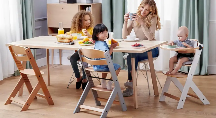 Familjen samlas kring bordet, barnen sitter i sina kinderkraft enock barnstolar och njuter av frukosten.