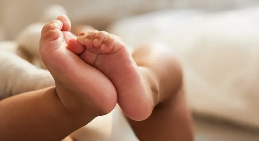 Små babyfötter vilar mot en mjuk kudde. Kanske snart dags för en potta med ljud för att öva på att bli stor.