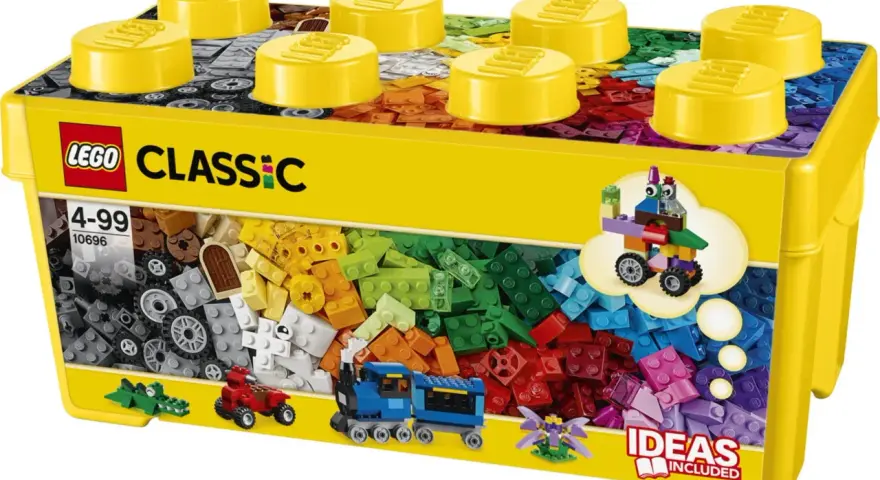 En gul låda med LEGO Classic stor samling, fylld med färgglada byggklossar. En tåg, en bil och en krokodil syns också.