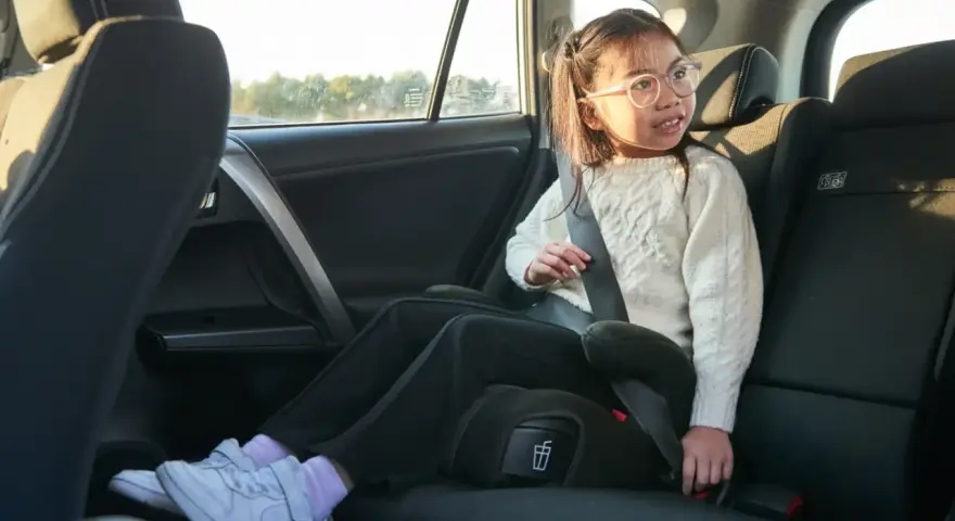 Flicka i bilens baksäte sitter på bälteskuddar och är fastspänd.
