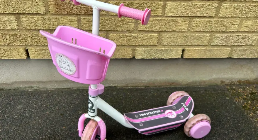 En rosa stiga sparkcykel trehjuling med korg framtill, redo för äventyr.