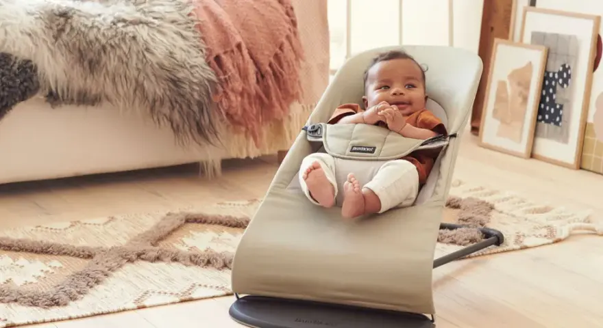 Söt bebis i beige Babybjörn babysitter. Denna babysitter klarar en babybjörn babysitter maxvikt på 13 kg.