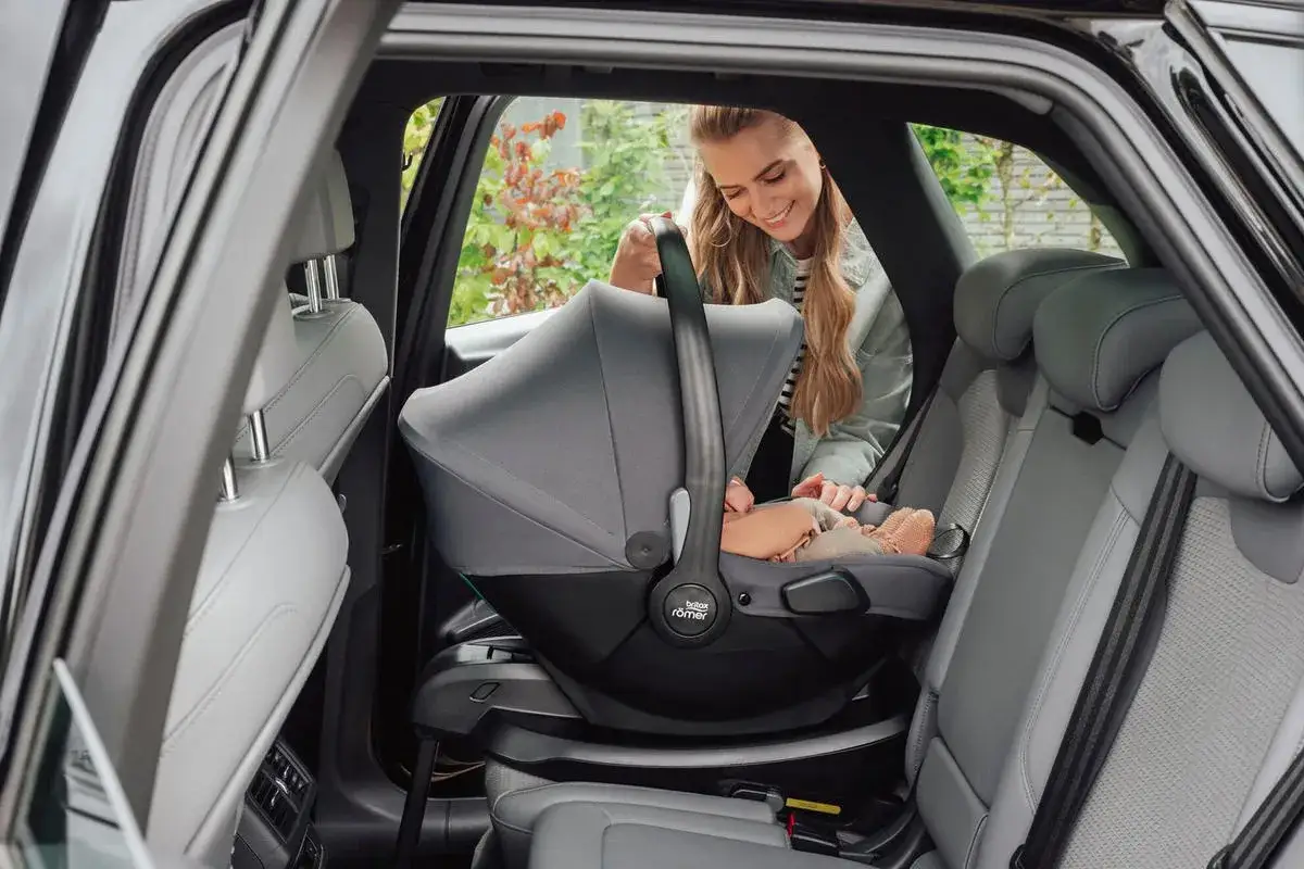 Glad mamma sätter i Britax Baby Safe Core bilbarnstol med baby i bilen.