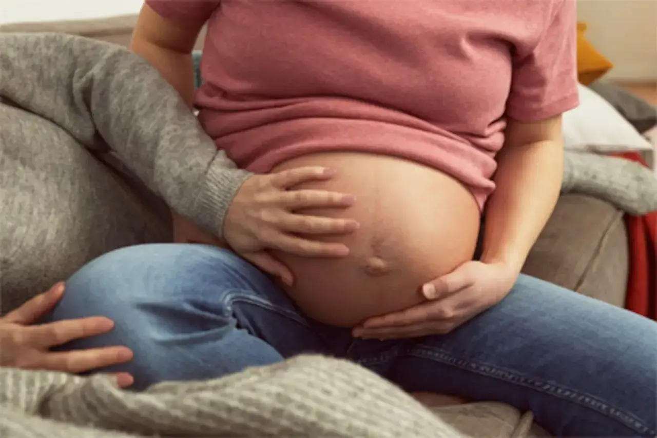 Gravid mage med h&auml;nder som smeker den, en symbol f&ouml;r tecken p&aring; stressad bebis i magen.